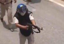 A police officer aiming an AK-47 at protesters in Siwan, Bihar.