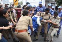 Police personnel detaining a woman protester during a demonstration in Delhi. Protestors are demanding the resignation of Chief Election Commissioner Gyanesh Kumar.