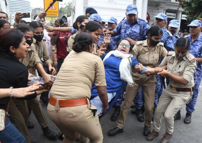 Police personnel detaining a woman protester during a demonstration in Delhi. Protestors are demanding the resignation of Chief Election Commissioner Gyanesh Kumar. Police personnel detaining a woman protester during a demonstration in Delhi. Protestors are demanding the resignation of Chief Election Commissioner Gyanesh Kumar.